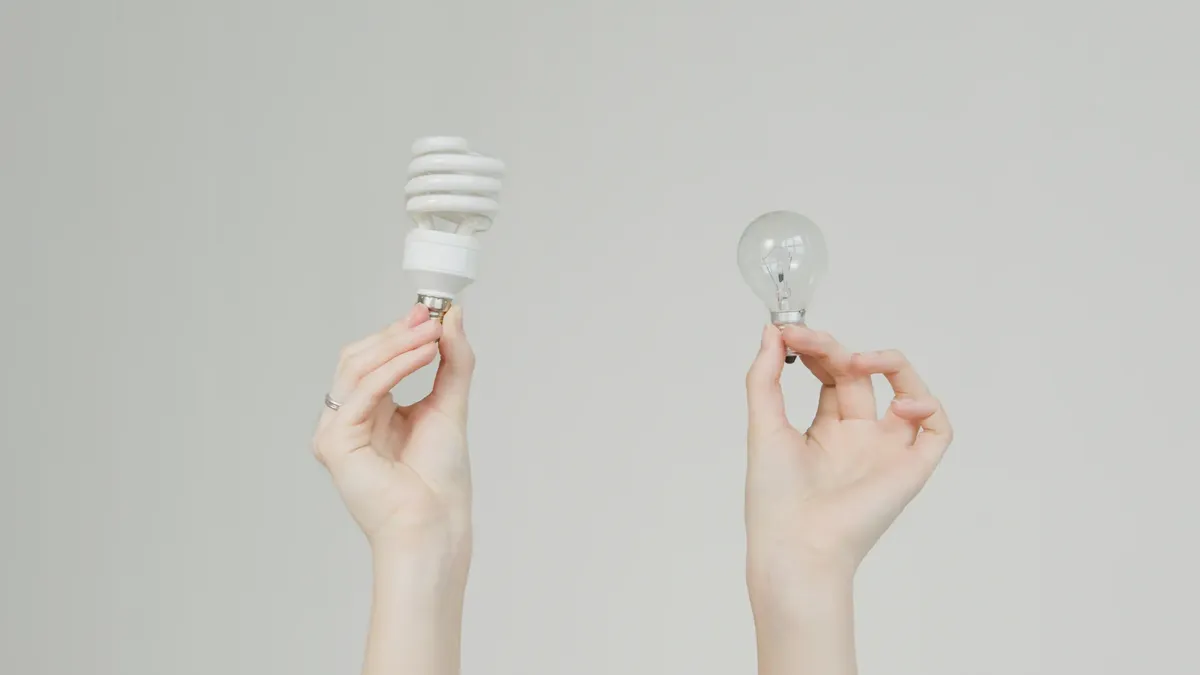Hands hold incandescent and spiral light bulbs, symbolizing energy efficiency.