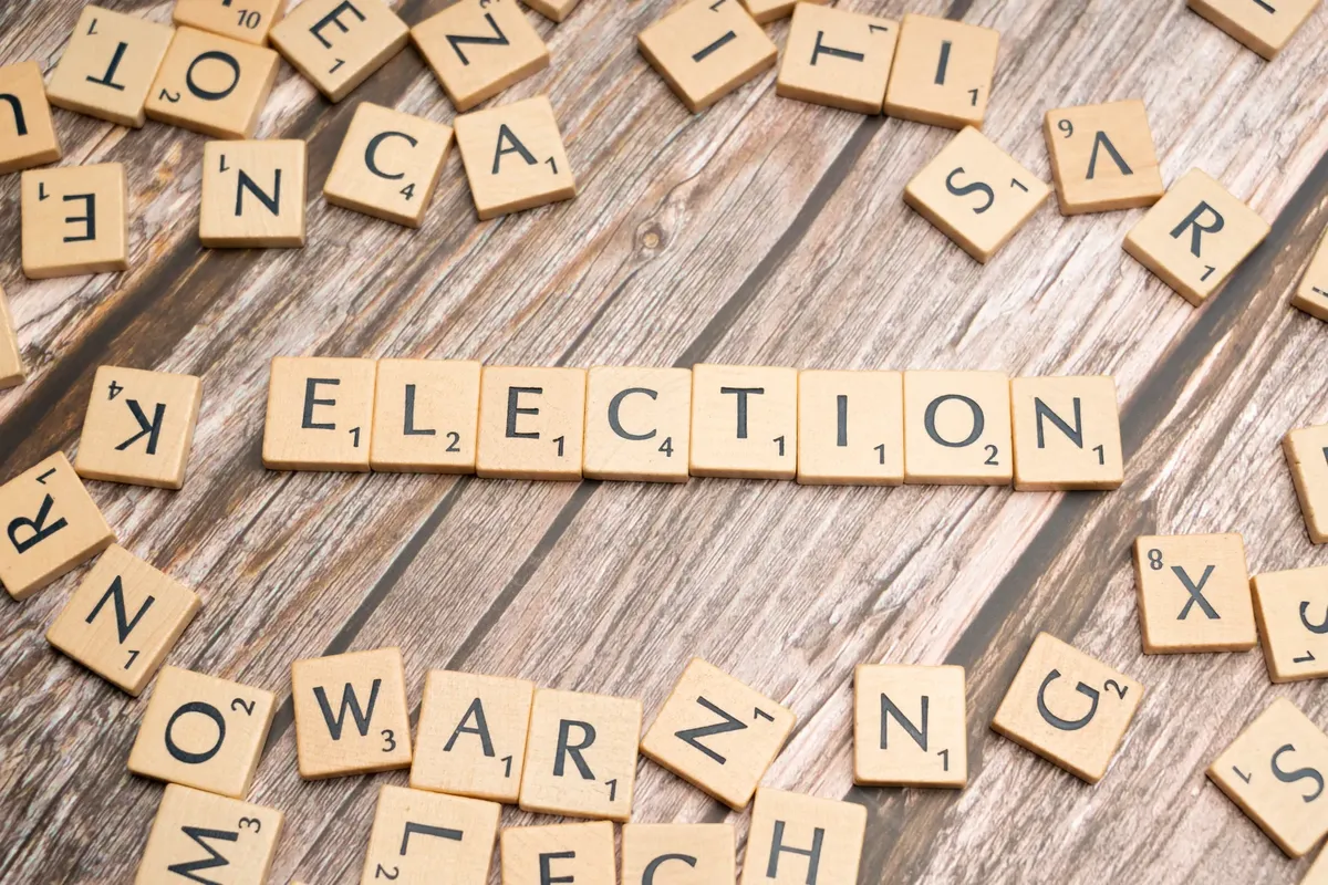 Wooden letter tiles form the word 'election' on a textured wooden surface, symbolizing voting.